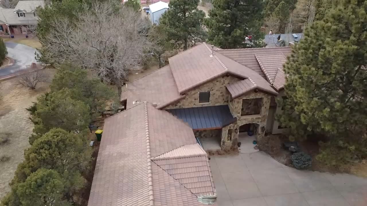 Concrete S-tile roof with standing-seam metal accent over the entry porch, custom Front Range estate